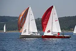 Das Bild zeigt zwei 16m²-Jollenkreuzer mit gesetzten Spinnaker in einer Wettfahrt auf dem Großen Brombachsee