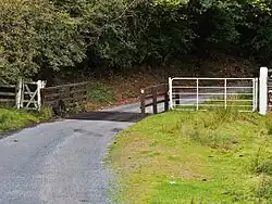 Das weiße Gatter ermöglicht es Pferdewagen, Reitern und getriebenem Vieh, die Sperre zu umgehen. Links ein Fußgängertor.