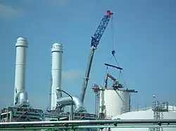 Spinnenkran an einem Kranausleger für die letzten Meter, daneben die zwei neuen 50 Meter hohen Schornsteine (18. Juni 2018)