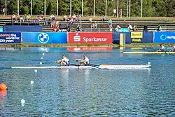 Zwei Ruderer im niederländischen Nationaltrikot rudern in einem weißen Boot auf der Bahn 5. Ritsema schaut geradeaus, während sein Hintermann zur Seite sieht.