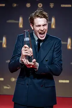 Philip Froissant mit jubelnd-verzerrtem Gesichtsausdruck, den deutschen Fernsehpreis 2023 in den Händen haltend
