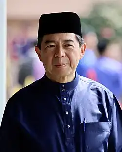 Amin Liew 2023. Ein chinesischer älterer Herr mit blauem Seidenhemd und einer indonesischen moslemischen Kopfbedeckung.