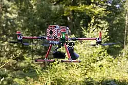 Eine großer, roter Quadcopter mit der Aufschrift "Feuerwehr Köln". Erkennbar ist ein Hornlautsprecher unter der Drohne