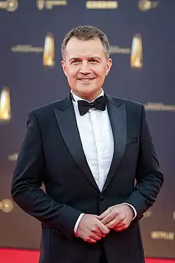 Christopher Wittich in Black Tie vor dunkler Sponsorenwand