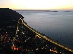 This view of Penmaenmawr at sunset shows how the modern A55 Expressway bypasses the older road through the town centre before resuming the original route around the headland.