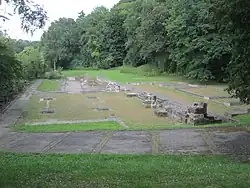 Gesamtansicht der erhaltenen Ruinen der Abtei von Clairlieu (2012) mit durch Steine markierten Standorte der zerstörten Klostergebäude auf kurzgeschoren Rasenflächen als Panoramadarstellung und umlaufenden Wald in Farbe.