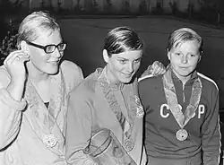 Auf diesem Schwarzweißfoto trägt Ada Kok einen Bademantel, Mandonnaud und Sosnowa tragen Trainingsanzüge. Alle drei Schwimmerinnen tragen eine Medaille um den Hals.