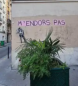 An einer hellen Hauswand ist der handgeschriebene Schriftzug „M’endors pas“ zu sehen.