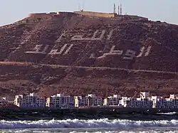 Bucht und Kasbah heute. Die Schrift auf dem Berg ist der Wahlspruch Marokkos: Gott, Vaterland, König (Arab.: الله، الوطن، الملك DMG Allāh, al-Watan, al-Malik)