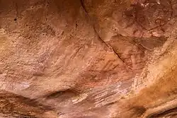 Geometrischer Kreis in Rot mit davon ausgehenden Strahlen und Handabdrücke