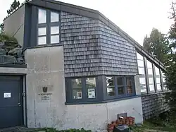 Ein Gebäude mit Holzschindeln, Mauer und Fenster. Das Forschungslabor des Alpengartens am Patscherkofel.