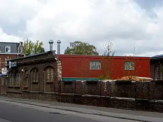 Alte Vorderwand der Maschinenhalle mit angebautem neuen Kantinengebäude; links im Hintergrund das Direktionsgebäude