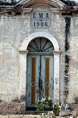 Eingang der alten Schule von 1906, mit den Insignien der früheren Stadtverwaltung (Câmara Municipal) von Ambriz (C.M.A.)