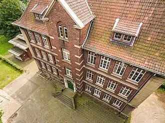 Luftbildaufnahme des heutigen Atelierhauses, ein altes Schulgebäude aus den vielleicht 30er Jahren. Aus ca. 25 Metern Höhe mit Blick auf das Dach und die Seite des Eingangs fotografiert.