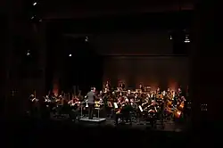 Orchester auf erleuchteten Bühne mit dunklem Zuschauerraum