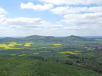 Blick vom Hohen Dörnberg westwärts zum Großen Bärenberg (mit Bärenbergturm; mittig links) mit Großem Gudenberg (rechts), Rohrberg (links) und Kernstadt von Zierenberg (mittig rechts)
