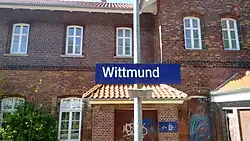 Bahnhofsschild mit Empfangsgebäude im Hintergrund (2017)