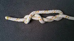 Nun nimmt man das Auge oder auch die Schlinge und legt sie nach oben. Beachtet aber dabei, dass sie rechts vom ersten Törn liegt