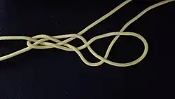 Das rechte untere Ende wird diagonal nach oben unter das Auge geführt.