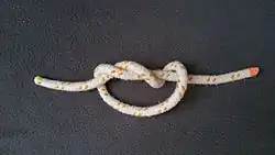 Man zieht leicht an beiden Enden des Seiles oder Fadens, der Knoten dreht sich beim Zuziehen um sich selbst.