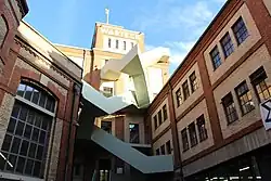 altes Backsteingebäude mit hellgrüner moderner Treppe davor