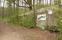 Stützmauer am Hang mit verwittertem Logo der Gilde Brauerei