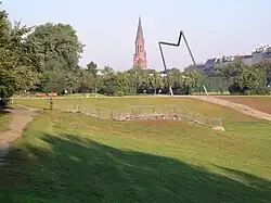 Skulptur Schreiten­der Mensch, hinten die Emmaus-Kirche