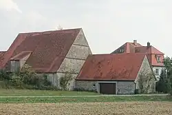 Drei Gebäude einschließlich dem Schlos in ländlicher Umgebung mit teilweise sichtbaren Schloss im Hintergrund.