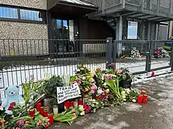 Blumen vor dem Eingang, darauf ein Schild mit der Aufschrift „Trauer – und Wut über das fehlende Waffenverbot“