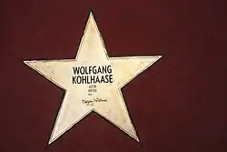 fünfzackiger, goldener Stern, eingelassen auf rotem Untergrund mit der Inschrift Wolfgang Kohlhaase, Autor, Writer, 1931 und Unterschrift