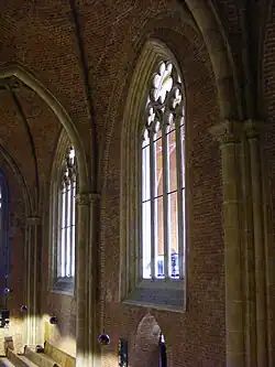 Inneres rechtes Seitenschiff: neugotische Maßwerkfenster zum äußeren Seitenschiff; in der Stirnwand Reste eines älteren Sandsteinbogens