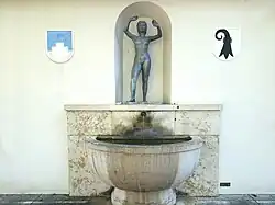 Brunnenskulptur (1925) von Hans Frei (1868–1947). Zur Vierhundert-Jahr-Feier der Vereinigung Riehens mit Basel. Bei der Tramhaltestelle Burgstrasse in Riehen, Basel, Schweiz