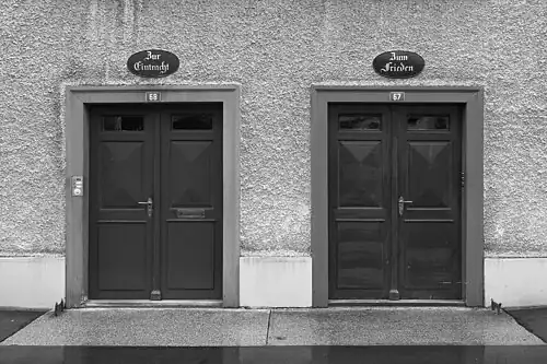 Eintracht und Friede – Die Ideale des Dorfes über den Eingängen eines Arbeiterhauses