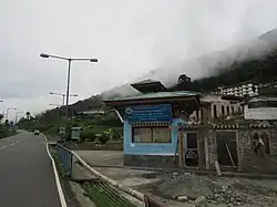 Baustelle von Gebäuden an einer neu gebauten Asphaltstraße mit traditionellem bhutanischen Dach.