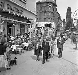 Blick über den Gehweg Richtung Gedächtniskirche, Menschen sitzen an Tischen vor dem Café Kranzler