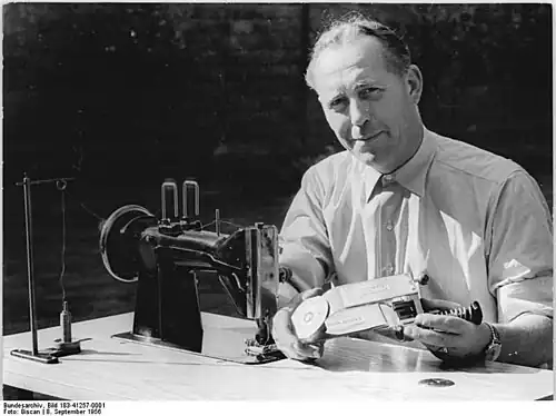Mechanikermeister Gerard Holze mit dem von ihm entwickelten Pikier-Apparat, einem Zusatzgerät für die Zickzack-Nähmaschine (Magdeburg 1956)