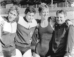 Schwarzweißfoto mit drei Schwimmerinnen in Trainingsjacke und einer im Badeanzug