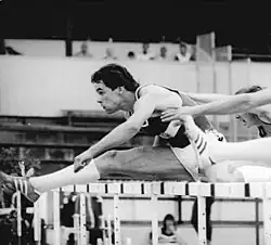 Schwarzweißfoto eines Hürdenlaufs mit Andreas Schlißke im dunklen Trikot und in weißer Hose, der in Führung liegt.