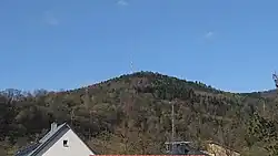 Der Sender Kirschfurt als weiß-roter Turm auf dem bewaldeten Burgberg bei Collenberg, von Freudenberg aus gesehen