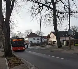 Bushaltestelle Borchsholt mit typischen Häusern in Hammersbeck und Bus der Linie 98.