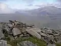Ein Cairn am Ostende des Gipfelplateaus des Beinn Liath Mhòr Fannaich, im Hintergrund der Beinn Dearg