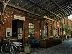 Auf dem Bild zu sehen ist der Eingangs der Cammerspiele Leipzig, eine Tür in einer ehemaligen Fabrikhalle aus roten Ziegeln