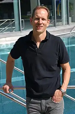 Christian Tröger steht in entspannter Haltung vor einem Freibecken.