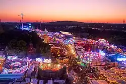 Beleuchtete Buden und Fahrgeschäfte im Abendrot