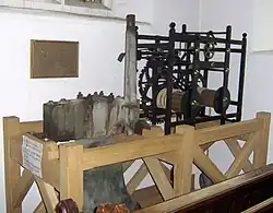 Hölzerner Rahmen, der einen Mechanismus aus Metall enthält.