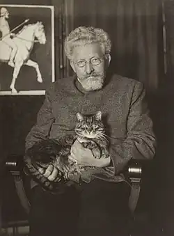 Der bereits grauhaarige Michael Georg Conrad mit Katze auf dem Schoß in seiner Wohnung. Aufnahme undatiert.
