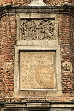 Symbole der Gerichtsbarkeit der Stadt Düsseldorf (rechts, mit dem Bergischen Löwen, einen Anker haltend) und Wappen der Vereinigten Herzogtümer Jülich-Kleve-Berg (links, ohne die Wappenfelder für das Herzogtum Geldern und die Grafschaft Zutphen, auf die Herzog Wilhelm 1543 im Vertrag von Venlo hatte verzichten müssen)
