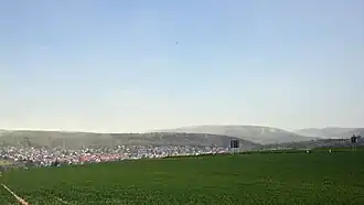 Blick von einem Fahrweg nahe der Kreuzung der Kreisstraßen 4&nbsp;und&nbsp;6 südwestlich von Nieste über das Dorf im Niestetal hinweg ostnordostwärts zum Haferberg; rechts der Berg Mühlenstein