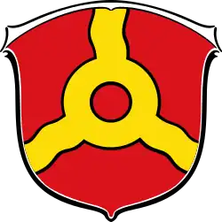 „In Rot ein goldener Ring, von dem göpelförmig drei gewellte goldene Bänder bis zu den Schildrändern ausgehen..“