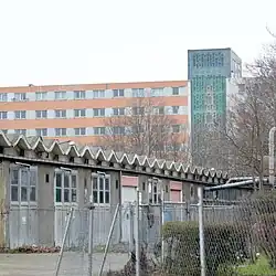 mehrere graue alte Garagenzufahrten hinter einem hohen siebenstöckigem Gebäude